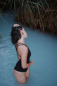 High angle view of young woman wearing bikini while standing in lake