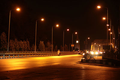 Illuminated street lights on sidewalk in city at night