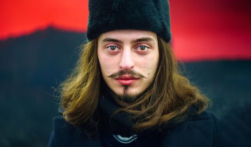 Close-up portrait of man in warm clothing standing against wall