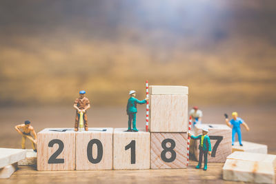 Figurines working over toy blocks with numbers on table