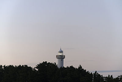 Lighthouse by sea against clear sky