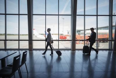 Side view of business people walking with luggage at airport