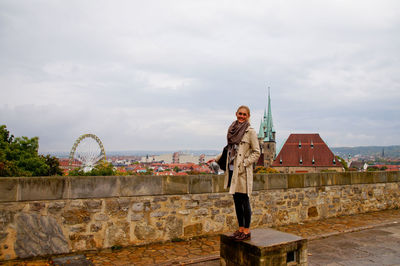 Full length of woman standing against sky in city