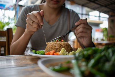 Midsection of woman eating thai food in restaurant.