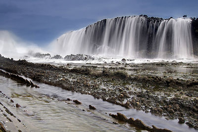 Scenic view of waterfall against sky