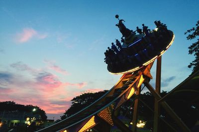 Low angle view of silhouette carousel against sky