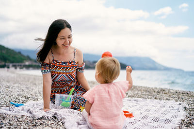 Mother and daughter on beach against sky