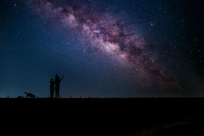 Silhouette family against sky at night