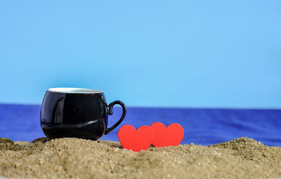 Close-up of heart shape on beach against clear blue sky