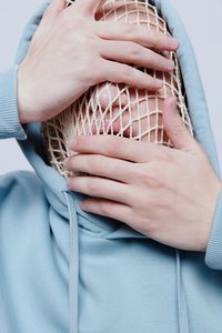 Man wearing mesh bag covering face with hands