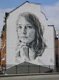 Portrait of young woman against building against sky