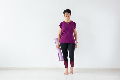 Portrait of a young woman standing against wall