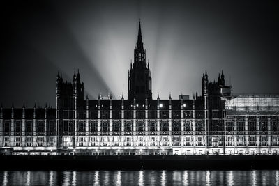 River by illuminated buildings against sky at night