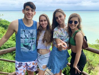 Portrait of smiling young women standing against water