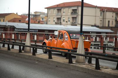 Orange vintage car on bridge in city