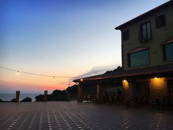 Street amidst buildings against sky at sunset