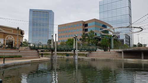 Buildings by canal against sky in city