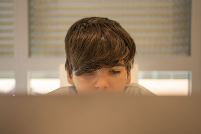 Young caucasian school boy studying behind his laptop