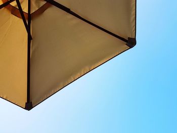 Low angle view of parasol against clear blue sky