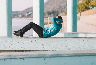 Side view of young man lying on retaining wall