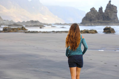 Rear view of woman standing on beach
