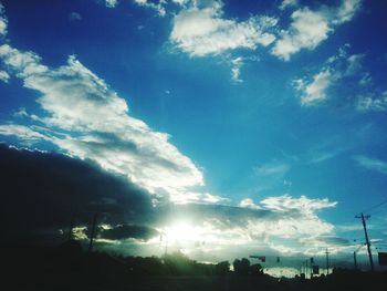 Low angle view of silhouette trees against cloudy sky