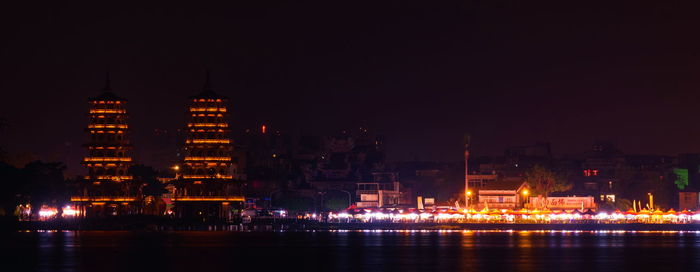 Illuminated buildings against clear sky at night