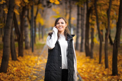 Young woman standing in forest during autumn