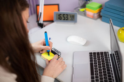 A young girl is scrawling words in english on small pieces of paper.