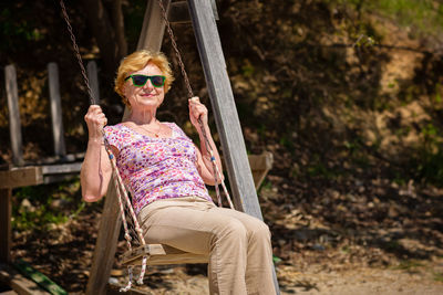 Senior woman joyfully swinging on a swing and having fan