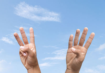 Low angle view of human hand against sky