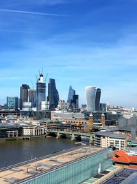 Modern buildings by river against sky in city