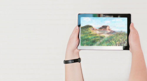 Midsection of woman holding mobile phone against wall