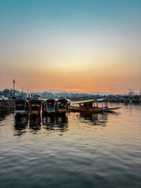 Boats in sea against sky during sunset