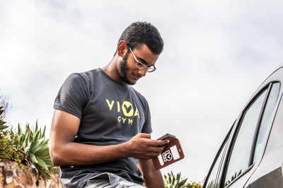 Man using smart phone against sky