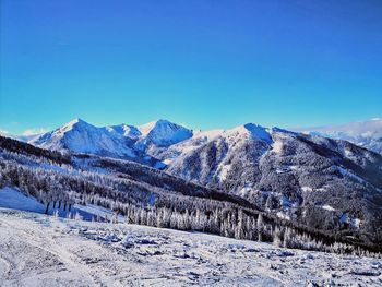 Scenic view of snowcapped mountains against clear blue sky