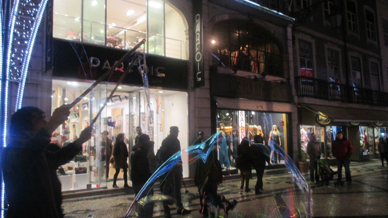 PEOPLE WALKING ON ILLUMINATED STREET AT NIGHT