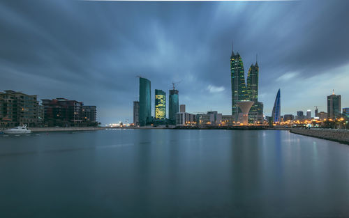 City at waterfront against cloudy sky