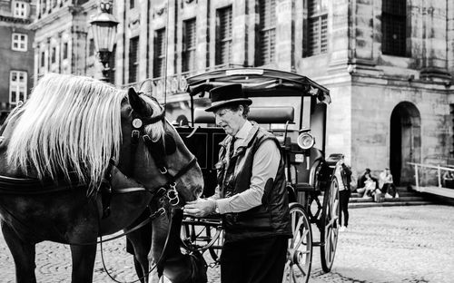 Man standing by horse cart on street in city