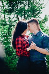 Side view of young couple standing face to face in forest