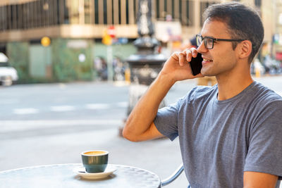 Midsection of man holding coffee cup on table in city