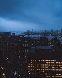 Silhouette manhattan bridge over east river amidst city at night