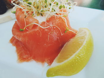 Close-up of smoked salmon by lemon in plate