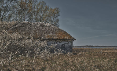 Abandoned house on field against sky