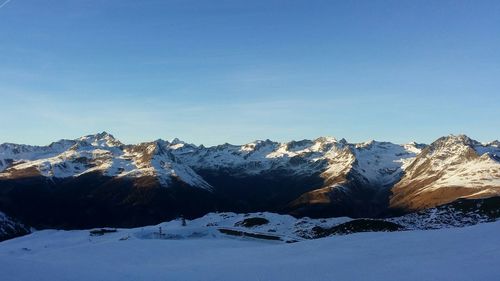 Scenic view of snowcapped mountains against blue sky