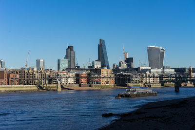 Scenic view of river by buildings against clear blue sky