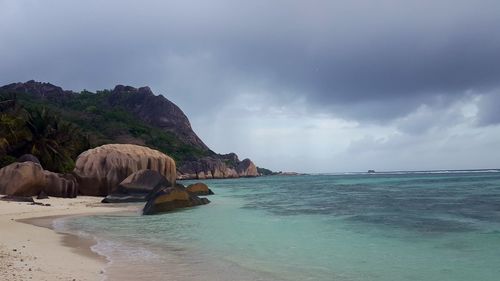 View of calm beach against cloudy sky