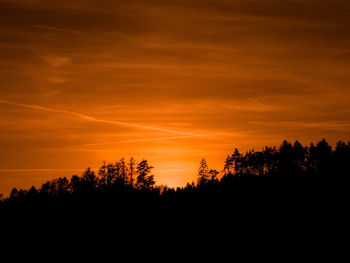 Silhouette trees against dramatic sky during sunset