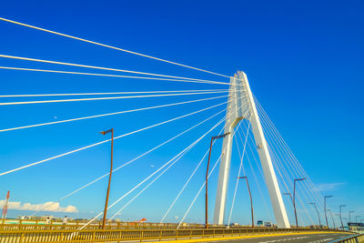 Low angle view of suspension bridge against clear blue sky