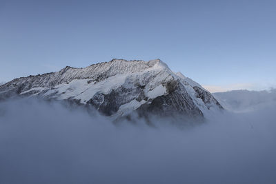 Low angle view of snowcapped mountains against clear blue sky